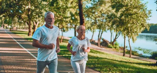 Senior couple is doing sport outdoors. Running in park in the morning.