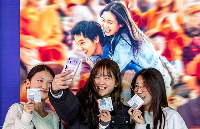 Movie-goers take selfies in front of a movie poster at a theater in Qianxi City, southwest China's Guizhou Province, Feb. 18, 2024. (Photo by Fan Hui/Xinhua)