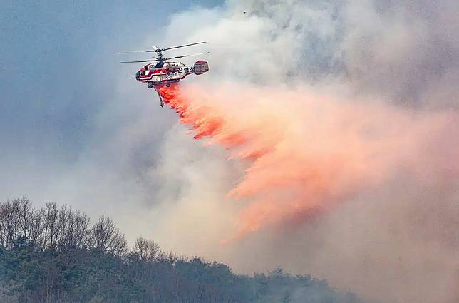 A Korea Forest Service helicopter dumps fire retardant on a wildfire in Uiseong, South Korea, Monday, March 24, 2025. (Yoon Gwan-shick/Yonhap via AP)