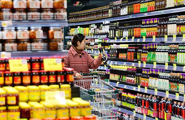 A customer selects condiments at a supermarket in Wuxi, east China's Jiangsu Province, Dec. 9, 2024. (Photo by Huan Yueliang/Xinhua)