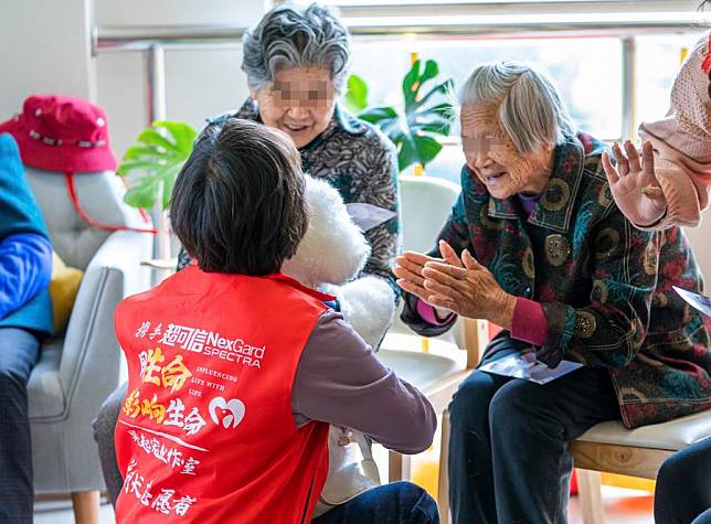 Seniors interact with a therapy dog at a support center for the elderly with cognitive disorders in Shanghai, east China, April 25, 2023. (Xinhua)