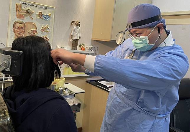 醫師陳建志為頭痛患者清除兩耳塞滿的耳垢。（醫師陳建志提供）
