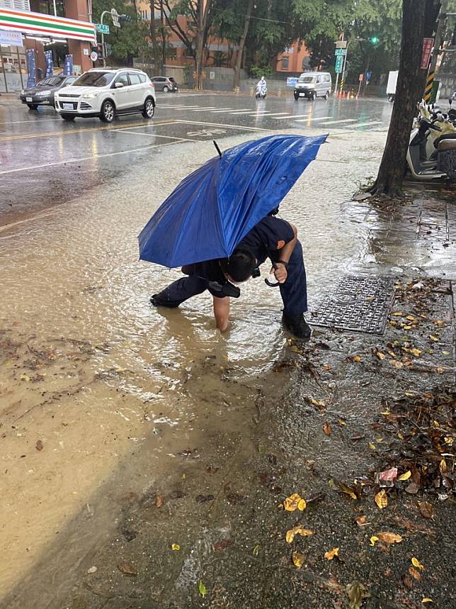 左營警分局警網執勤中見文慈路上水溝塞滿樹枝，造成積水，車輛通行不便，警網隨即下車，以徒手方式清除阻塞的樹枝，讓積水退去，車輛順暢通行。（記者陳左鈞攝）