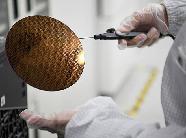 A researcher displays a wafer product at Shaanxi Institute of Advanced OEIC Technologies Co., Ltd. in Xi'an, northwest China's Shaanxi Province, March 4, 2024. (Xinhua/Zhang Bowen)