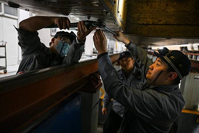 Technicians maintain the bottom of a bullet train at a train depot in Hohhot, north China's Inner Mongolia Autonomous Region, Jan. 17, 2025. (Xinhua/Lian Zhen)