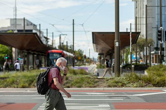 A man walks past a light rail station in Canberra, Australia on Dec. 1, 2021. (Photo by Chu Chen/Xinhua)