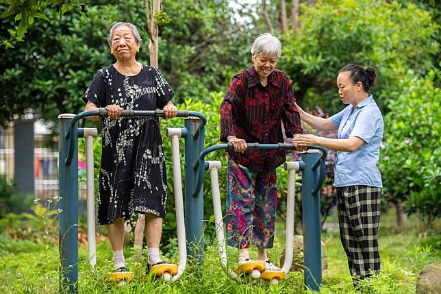 Senior residents exercise with the help of a staff member at a social welfare center in Hanshou County of Changde City, central China's Hunan Province, June 20, 2023. (Xinhua/Chen Sihan)