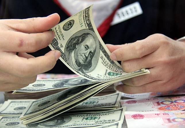 File photo shows a worker counts the U.S. dollars at a bank in Tancheng County of Linyi City, east China's Shandong Province. (Xinhua/Zhang Chunlei)