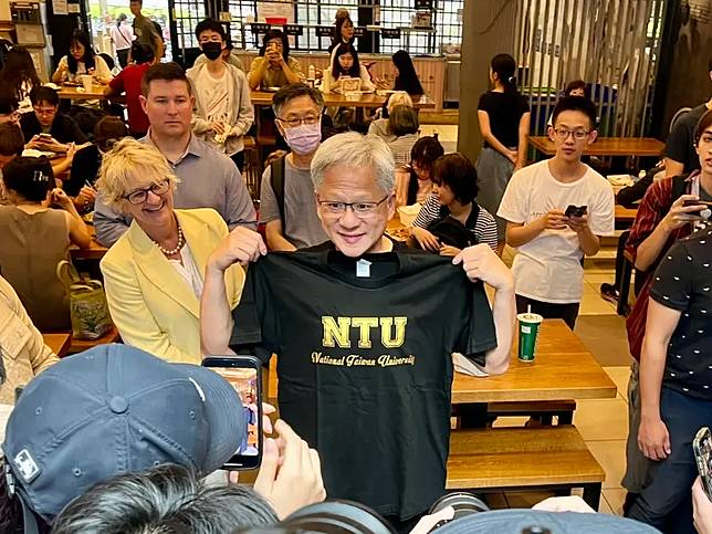 黃仁勳拿到台大校長陳文章致贈的NTU T-SHIRT，十分開心的拿出來比量。