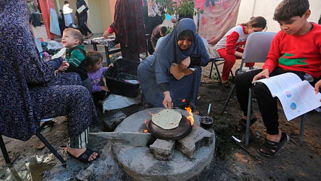 2023年11月16日，加薩南部拉法（Rafah），民眾用簡陋的廚具烘餅。美聯社