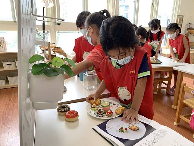 桃園市立蘆竹幼兒園品妍老師引導幼生在「扮家家酒」中，透過擺桌、擺盤、花藝等操作。（教育部提供）