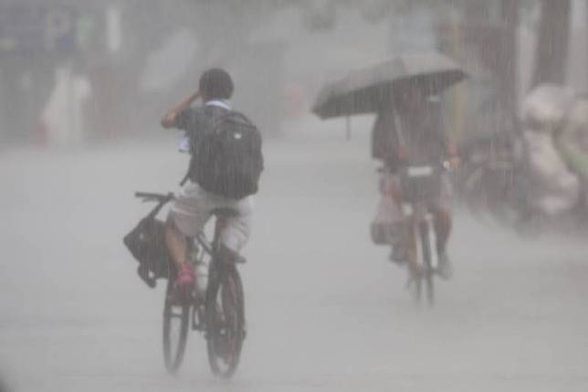 中央氣象署28日下午發布新北市、台北市、桃園市等 10縣市大雨特報。台北市公館商圈下午突然下起大雷 雨，有民眾騎單車來不及躲雨，在大雨中騎行。 中央社記者王飛華攝 113年6月28日