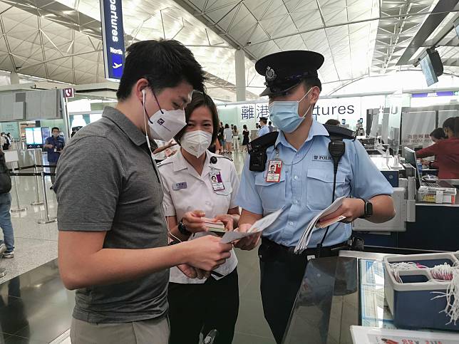 警方和入境處人員在機場派單張，呼籲前往東南亞等地旅客小心求職騙案。(資料圖片)