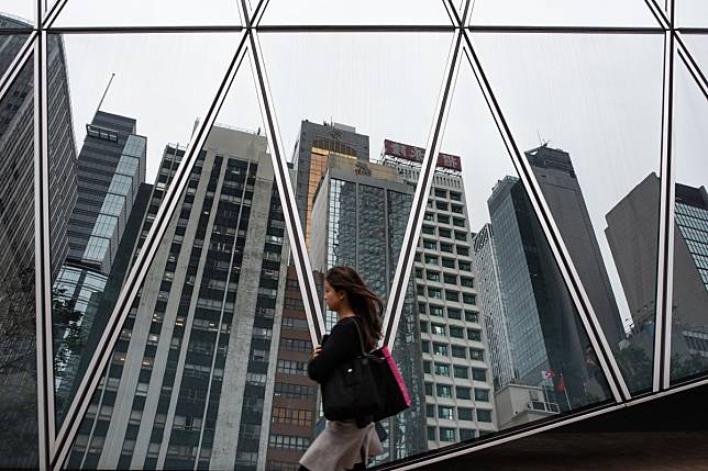 A woman walks past a reflection of the skyline of Hong Kong’s central business district on May 8, 2019. Hong Kong is near the top of US fund research firm Morningstar’s global gender diversity rankings for fund managers and chartered financial analysts, well ahead of Britain and the US. Photo: AFP