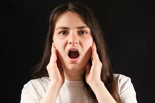 A,Woman,With,An,Open,Mouth,Holds,Her,Cheeks,With