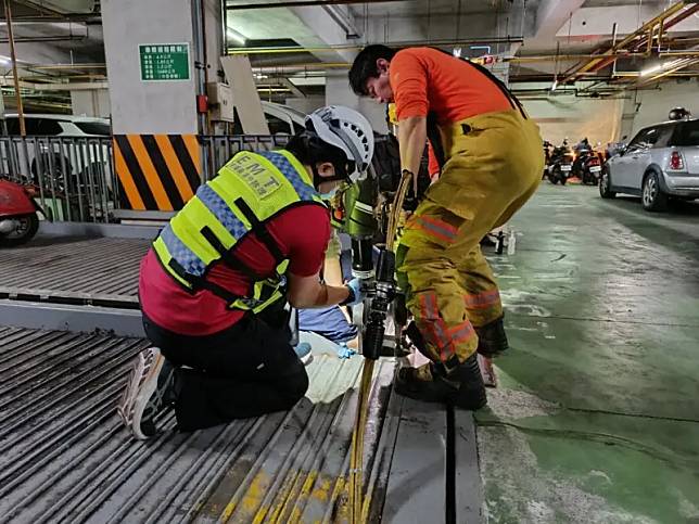 內埔鄉一棟大樓有住戶停車後，下車不慎踩進縫隙，整條腿卡在舊式機械車位裡。（圖／屏東縣消防局提供）