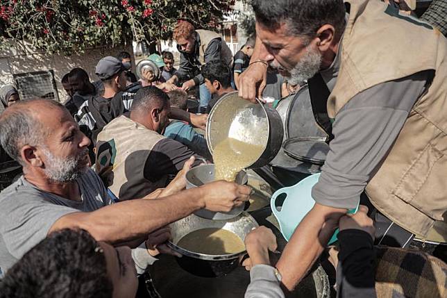 Palestinians receive free food at a food distribution center in the city of Deir al-Balah, central Gaza Strip, on Nov. 23, 2024. (Photo by Rizek Abdeljawad/Xinhua)