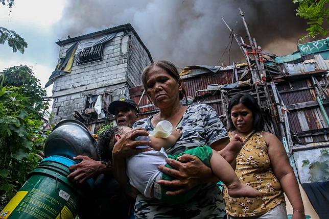 Residents evacuate with their belongings as a huge fire engulfs a slum area in Manila, the Philippines on Nov. 24, 2024.(Xinhua/Rouelle Umali)