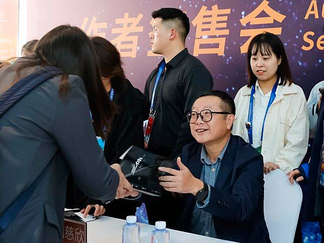 Hugo Award winner Liu Cixin (front R) autographs for sci-fi lovers during the 81st World Science Fiction Convention (WorldCon) in Chengdu, southwest China's Sichuan Province, Oct. 20, 2023. (Xinhua/Shen Bohan)