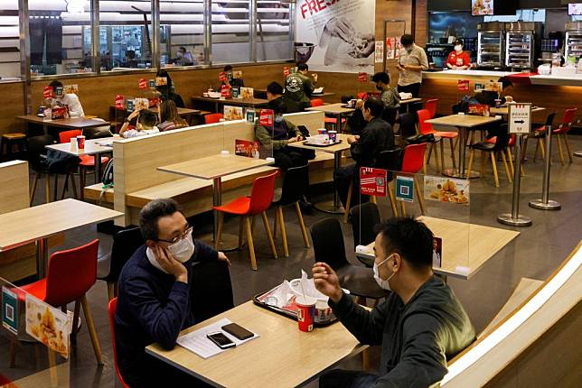 香港第5波疫情可能已來臨，港府再次勒令餐館晚上禁止內用。圖為民眾白天在餐廳內帶有隔板的餐桌上用餐。 （路透）