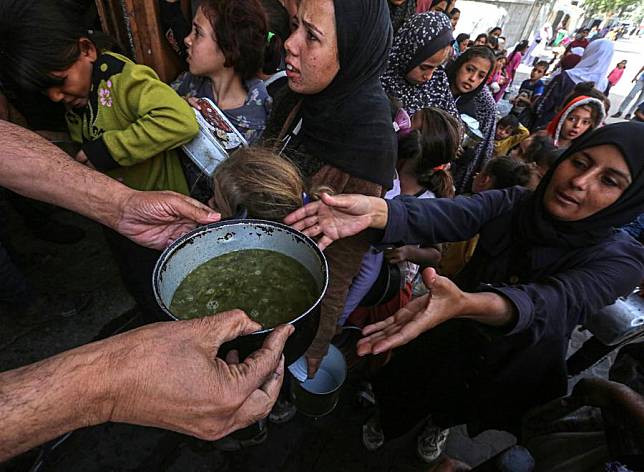 A Palestinian woman receives food at a food distribution center in the city of Deir al-Balah in central Gaza Strip, on Oct. 25, 2024. (Photo by Rizek Abdeljawad/Xinhua)