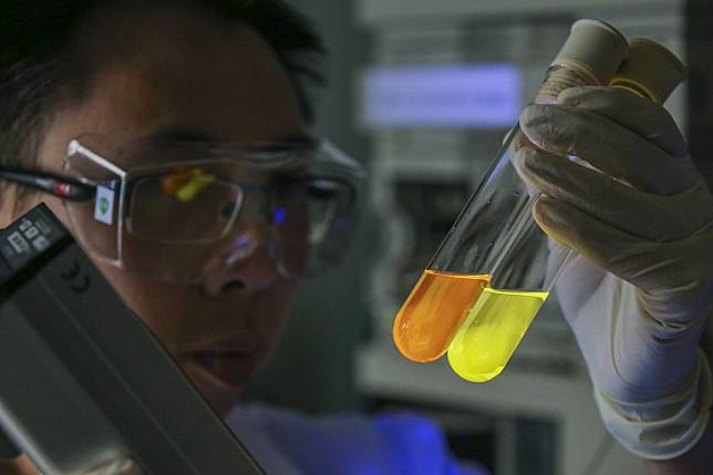 Dr. To Wai-Pong examines luminescent materials developed by the Laboratory of Synthetic Chemistry at the University of Hong Kong. Photo: SCMP / Dickson Lee