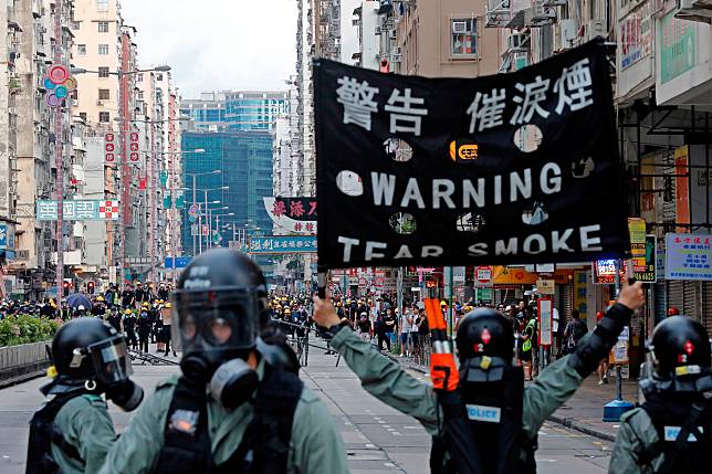 A riot police raises a warning flag as they try to disperse anti-extradition bill protesters by tear gas at Sham Shui Po in Hong Kong