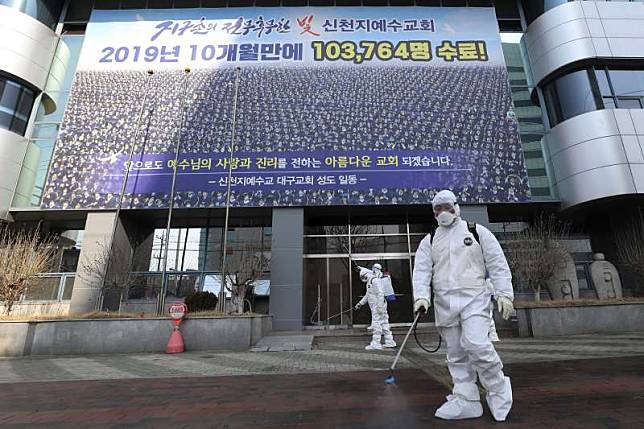 2月20日，全身穿著防護裝備的工作人員在南韓大邱新天地教會建築物進行消毒（美聯社）