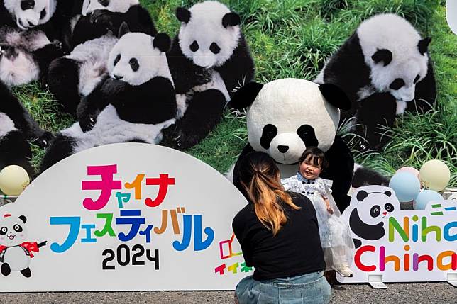 A woman takes a picture of her child with a giant panda doll during China Festival 2024 at Yoyogi Park in Tokyo, Japan, Sept. 7, 2024. (Xinhua/Zhang Xiaoyu)