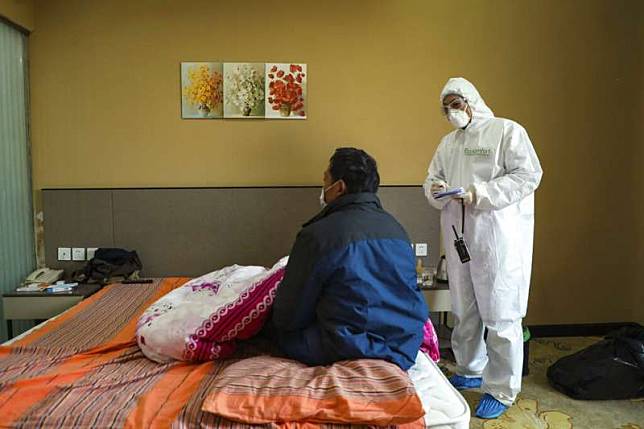 武漢一間收容隔離病患的旅館，身著全套防護服的工作人員正在照顧患者。（美聯社）