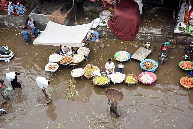 Vendors sell goods on a flooded road after heavy rain in Lahore, Pakistan on July 1, 2024. (Photo by Sajjad/Xinhua)