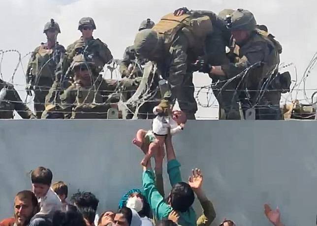 在美軍撤離阿富汗行動期間，小女嬰莉亞被海軍士兵一把拉起，準備交到一旁同樣身穿軍服的父親哈米德手上的照片傳遍全球，成為最能代表現場混亂局面的照片。 路透社 / 達志影像