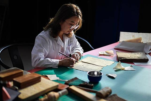 Zhang Hua, a restorer of ancient books in the library of Jilin University, works on the restoration of an ancient book at the library of Jilin University in Changchun, northeast China's Jilin Province, April 19, 2024. (Xinhua/Xu Chang)