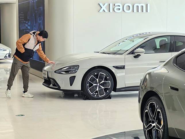 A consumer learns about Xiaomi's new energy vehicle model SU7 at a retail shop in Beijing, capital of China, March 28, 2024. (Xinhua/Ju Huanzong)