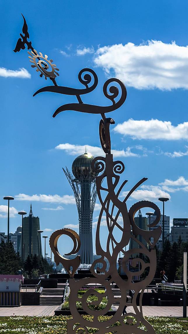 This photo taken with a mobile phone shows a sculpture and the Baiterek Tower in the background in Astana, Kazakhstan, June 29, 2024. (Xinhua/Wang Jianhua)