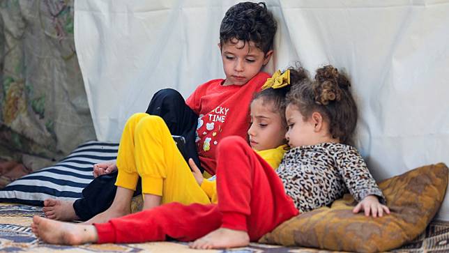 2023年11月5日，加薩市希法醫院外的難民帳篷裡，一名男童陪著兩個女童。路透社