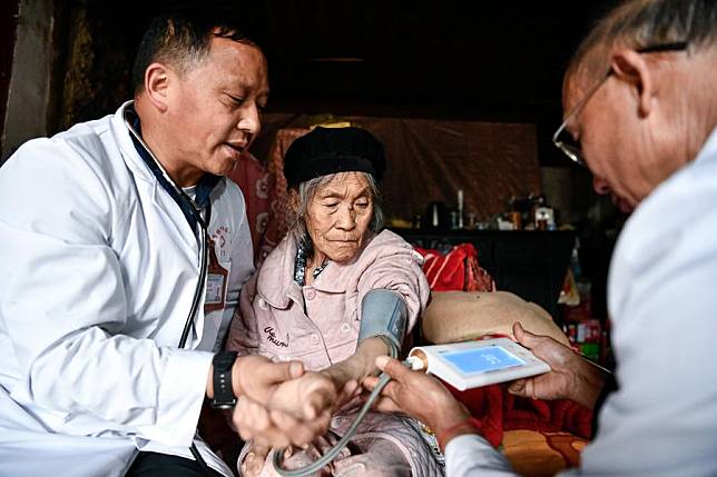 Zhu Daqing (L) and another doctor measure blood pressure of an elderly patient at the patient's house in Xinshui Village, Mazha Town of Yi-Hui-Miao Autonomous County of Weining, southwest China's Guizhou Province, July 19, 2023. (Xinhua/Yang Wenbin)