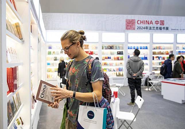 A visitor looks over a book at the Chinese publishers' exhibition area at the 76th Frankfurt Book Fair in Frankfurt, Germany, Oct. 17, 2024. (Xinhua/Zhang Fan)