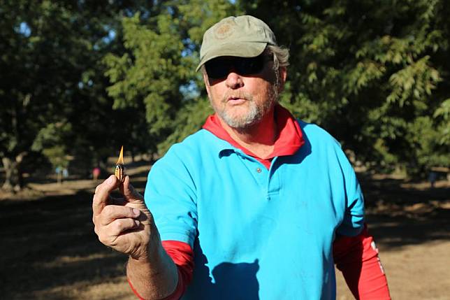 Randy Hudson, CEO of Hudson Pecan Company and former president of the U.S. Pecan Growers Council, kindles a fresh pecan flesh to demonstrate oil concentration in one of his orchards in Rochelle, Georgia, the United States, on Oct. 25, 2024. (Xinhua/Liu Yanan)