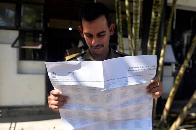 A policeman looks at a document that contains the names of candidates while waiting for his turn to cast postal vote for parliamentary election in Colombo, Sri Lanka on Oct. 30, 2024. (Gayan Sameera/Xinhua)