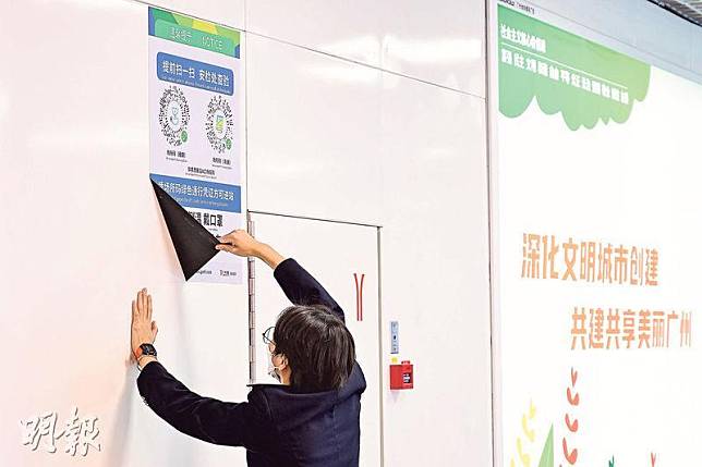 12月7日晚上，有廣州市地鐵工作人員撕掉入站口的健康碼掃碼指引。乘客進入車站無需再掃碼及出示健康碼。（中新社）