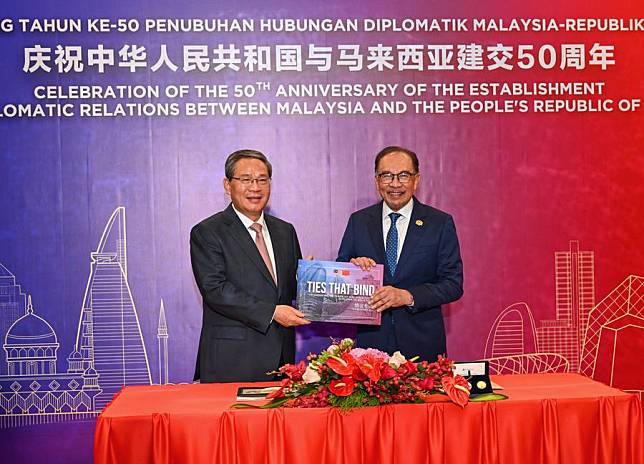 Chinese Premier Li Qiang and Malaysian Prime Minister Anwar Ibrahim present souvenirs to each other prior to the reception celebrating the 50th anniversary of the establishment of diplomatic relations between China and Malaysia and the Year of China-Malaysia Friendship in Kuala Lumpur, Malaysia, June 19, 2024. (Xinhua/Rao Aimin)