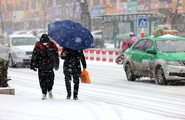 People walk on a street in the snow in Zaozhuang, east China's Shandong Province, Feb. 21, 2024. (Photo by Sun Zhongzhe/Xinhua)