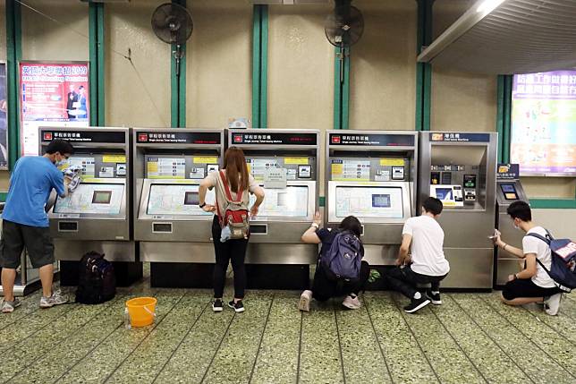 Youngsters clean up a ticket vending machine at Kwai Fong MTR station on Friday. Photo: K.Y. Cheng
