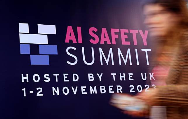 An attendee walks past a billboard of AI Safety Summit in Bletchley Park, Britain, Nov. 2, 2023. (Xinhua/Li Ying)