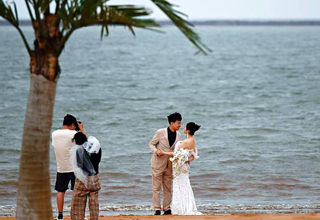 A couple poses for photos by the seaside in the Binhai New Area of north China's Tianjin, June 29, 2024. (Xinhua/Zhao Zishuo)