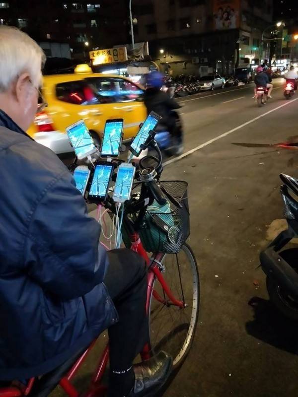 阿伯在腳踏車上裝了6支手機同時抓寶，被外國人封為「鐵血玩家」。(圖擷取自爆廢公社)