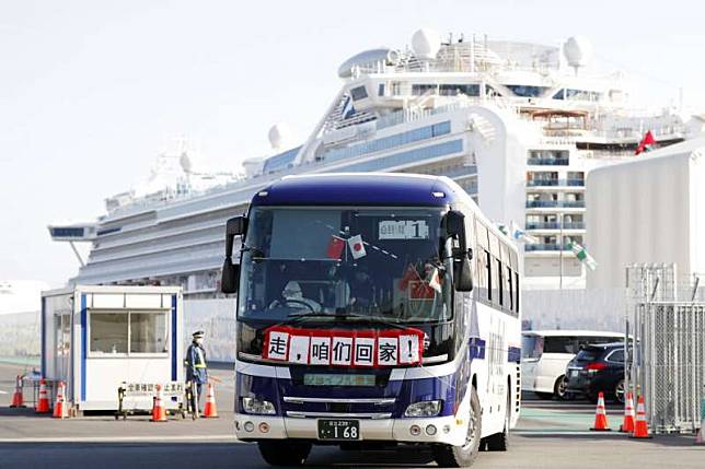 載運「鑽石公主號」香港乘客離開橫濱港的巴士，車前掛起了「走，咱們回家！」的布條。（美聯社）