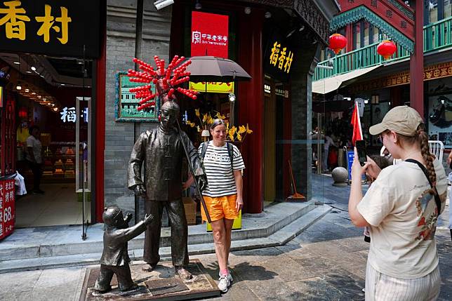 A tourist from Switzerland poses for a photo on Qianmen Street in Beijing, capital of China, July 10, 2024. (Xinhua/Ju Huanzong)