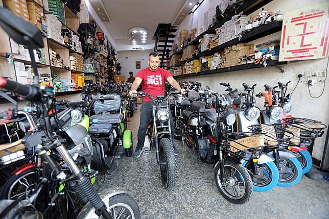 A customer tries out a China-made electric motorcycle at a shop at al-Sadriya market in Baghdad, Iraq, on April 16, 2024. (Xinhua/Khalil Dawood)